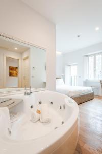 a white bathroom with a tub and a large mirror at Nikis Collection Trastevere in Rome