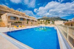 uma grande piscina com cadeiras e um edifício em Apartamento Manzanera 3 - PlusHolidays em Calpe