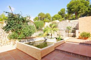 a garden with a pond and a stone wall at Villa Oasis - Plusholidays in Calpe