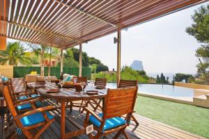 a wooden deck with a table and chairs under a pergola at Villa Oasis - Plusholidays in Calpe