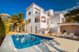 a villa with a swimming pool in front of a house at Villa Ibiza - PlusHolidays in Calpe