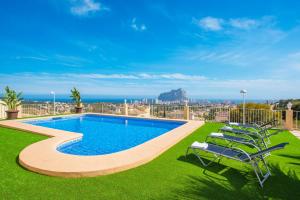 a swimming pool with lawn chairs and the ocean at Villa Maximo - PlusHolidays in Calpe