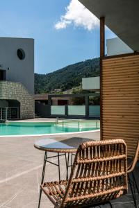 a wicker chair sitting next to a table next to a pool at La Isola Verde in Skala Potamias