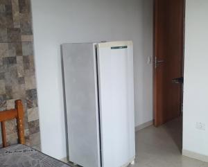 einen weißen Kühlschrank in einem Zimmer mit einer Wand in der Unterkunft Suíte praia de leste in Pontal do Paraná