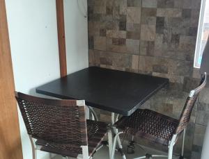 a black table with two chairs and a stone wall at Suíte praia de leste in Pontal do Paraná
