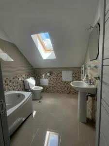 a bathroom with a sink toilet and a skylight at Pensiunea Vătafu in Gura Râului