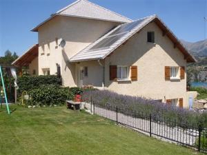 a house with a fence in front of a yard at La Tulipe **** in Savines