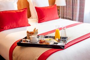 a tray of breakfast food on a bed at Le M & Spa Bordeaux Aéroport by Hôtels & Préférence in Mérignac