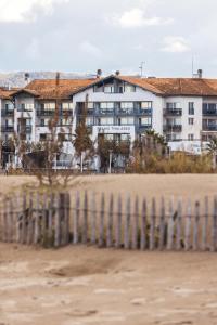 un bâtiment sur la plage avec une clôture dans l'établissement Hotel & Spa 4* Serge Blanco, à Hendaye