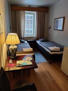 a room with two beds and a table with a lamp at Hotelli Merikotka in Kotka
