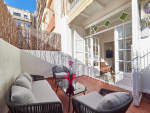 uma varanda com cadeiras e um vaso de flores em Barcelonaforrent The Living Apartment em Barcelona