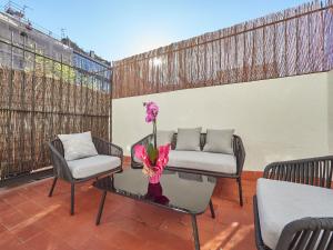 eine Terrasse mit 2 Stühlen und einem Tisch mit einer Blume darauf in der Unterkunft Barcelonaforrent The Living Apartment in Barcelona