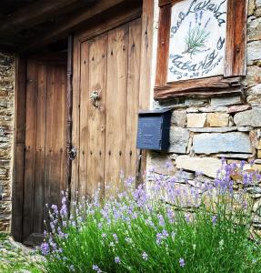 a stone building with a wooden door and some flowers at Lavanda Restaurant with Rooms in Kovačevica