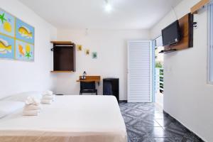 1 dormitorio con 1 cama blanca y TV en la pared en Pousada Remanso do Mar en Ubatuba