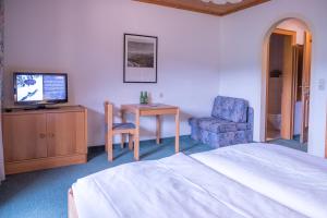 a bedroom with a bed and a tv and a chair at Die Pension - Margreiter in Saalbach-Hinterglemm