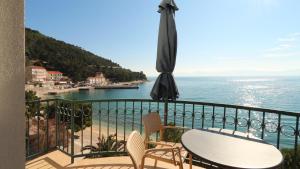 un balcón con una mesa y una sombrilla y el océano en Apartments on the beach-Drvenik, en Drvenik