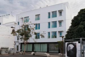 un edificio bianco con un albero di fronte di Alojamiento Santa Rosa Arrecife ad Arrecife
