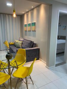 uma sala de estar com cadeiras amarelas e um sofá em Muro Alto Condomínio Clube Apt 316 em Porto de Galinhas