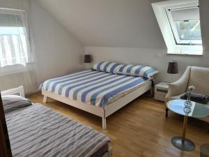 a bedroom with two beds and a chair and a window at Appartement Paradiso in Busingen am Hochrhein