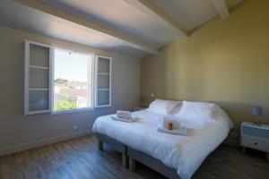 Un dormitorio con una gran cama blanca con ventana. en Appartement lumineux pour 6 personnes, en Le Bois-Plage-en-Ré