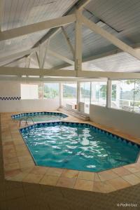 a large swimming pool with blue water in a building at Hotel Chalés Terra Nova in Itatiaia