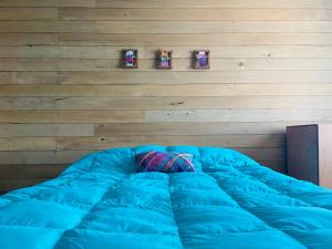 a large blue bed in a room with a wooden wall at Casa Apel Hostel in Puerto Varas
