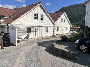ein weißes Haus mit einem davor geparkt in der Unterkunft Fjord Apartments in Dimmelsvik