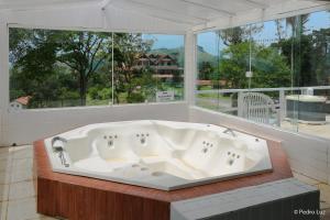 a bath tub in a room with a large window at Hotel Chalés Terra Nova in Itatiaia