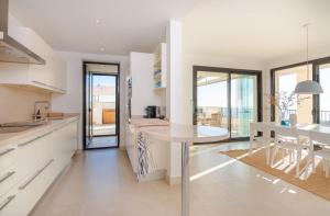 a kitchen with white cabinets and a table and a dining room at Luxurius Penthouse with Large Terrace and Spa in Marbella