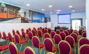 a conference room with red chairs and a screen at Hotel Condesa in Port d'Alcudia
