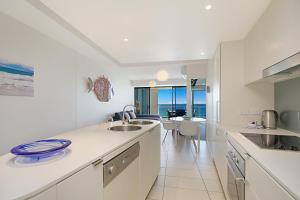 cocina con armarios blancos y vistas al océano en Blue C Coolangatta, en Gold Coast