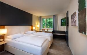 a hotel room with two beds and a window at Essential by Dorint Köln-Junkersdorf in Cologne