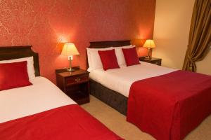 two beds in a hotel room with red walls at Anner Hotel in Thurles