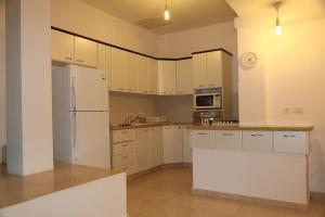 a kitchen with white cabinets and a refrigerator at Apartment Tal in the Judean Desert in Kfar Adumim
