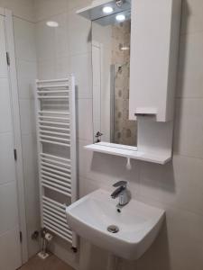 ein weißes Badezimmer mit einem Waschbecken und einem Spiegel in der Unterkunft Apartman Matija in Pale