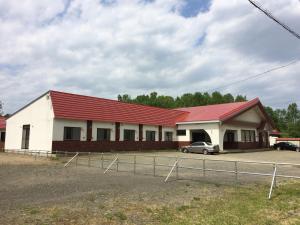 a building with a red roof and a parking lot at ビジネスホテル幸楽 in Abashiri