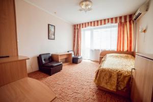 ein Hotelzimmer mit einem Bett und einem Stuhl in der Unterkunft ПОДІЛЛЯ in Winnyzja