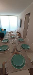 a table with green plates and wine glasses on it at Departamento Nuevo en Condominio Viña del Mar in Viña del Mar
