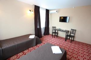 um quarto de hotel com duas camas e uma mesa e uma televisão em Troya Hotel em Rudny