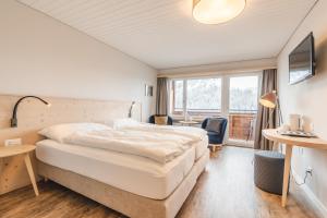 a hotel room with a large bed and a window at Hotel Alpensonne - Panoramazimmer & Restaurant in Arosa