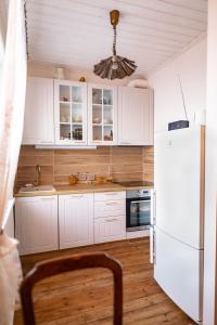 a kitchen with white cabinets and a white refrigerator at Campenhausen lodging in the heart of Kuressaare in Kuressaare