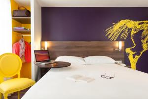 a bedroom with a bed with a laptop and a chair at ibis Styles Saumur Gare Centre in Saumur