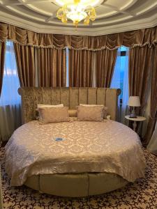 ゲレンジークにあるHotel Europaのベッドルーム1室(カーテンとシャンデリア付きの大型ベッド1台付)