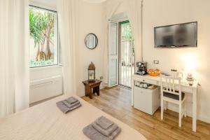 Camera bianca con scrivania e TV a parete. di GARDEN HOUSE - Luxury Guest House - Only Self Check in a Roma