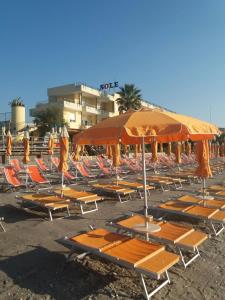 ein paar Stühle und Sonnenschirme am Strand in der Unterkunft Residence Sole in Albenga