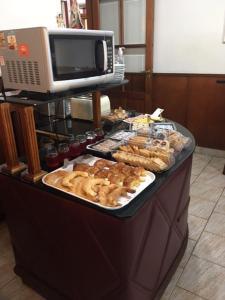 una línea de buffet con varios pasteles y un microondas en Patri Hotel en Chivilcoy