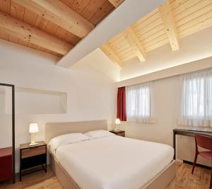 una camera da letto con un grande letto bianco e soffitti in legno di Crocevia - Locanda carsica contemporanea a Trieste