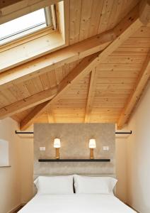 two beds in a bedroom with wooden ceilings at Crocevia - Locanda carsica contemporanea in Trieste