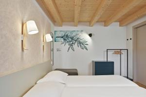 a bedroom with a white bed and a couch at Crocevia - Locanda carsica contemporanea in Trieste