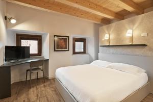 a bedroom with a bed and a desk with a television at Crocevia - Locanda carsica contemporanea in Trieste